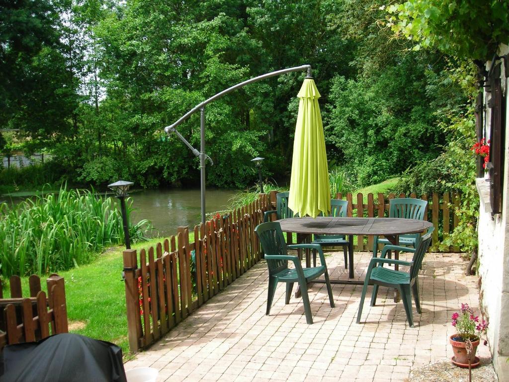 B&B riverside outdoor dining terrace with green chairs and parasol at Moulin St Blaise