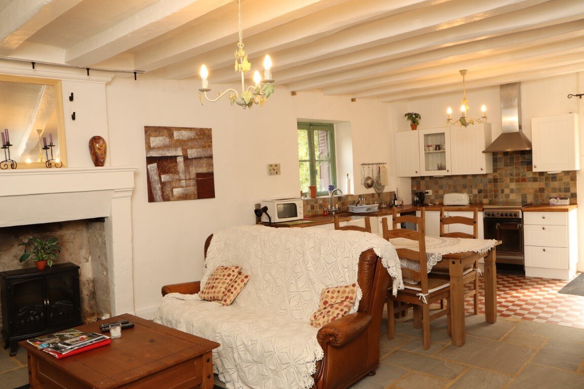 Open plan kitchen dining and living room of Gite La Maison du Frere with exposed beams and chandelier, Moulin St Blaise